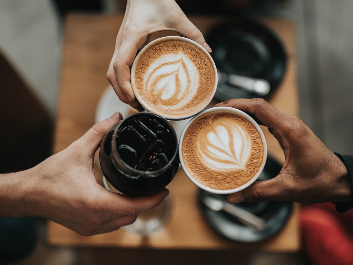Hands bringing coffee cups together in a warm toast